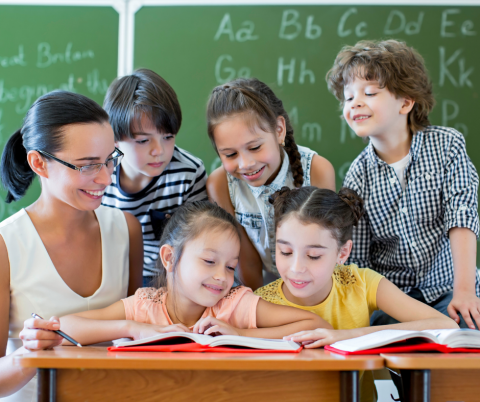 A teacher shows a group of students a book.