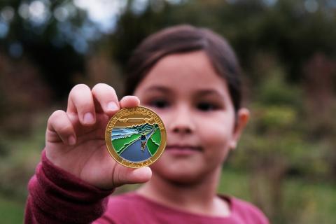 Junior geocacher, Margo Paquette, displays a limited-edition Raisin Region geocoin.