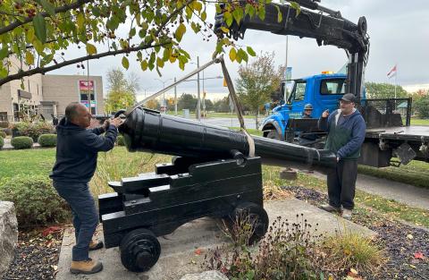 A cannon is lowered into position in front of the SDG Counties admin building.
