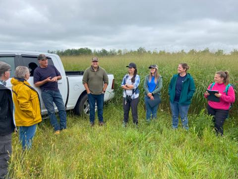 Farmer Ron Toonders (third from left) talks to guests about the benefits of switchgrass – visible in the background – for soil health during an ALUS stewardship tour in 2023.